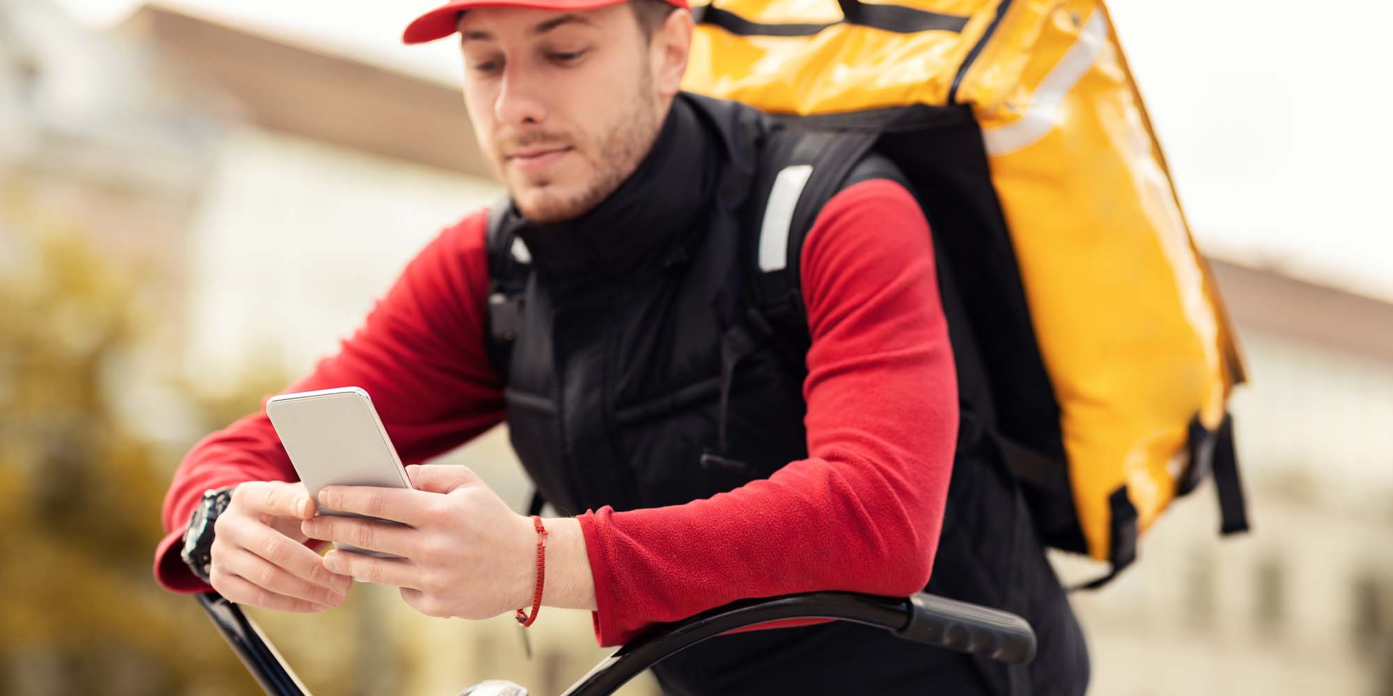 courier-using-delivery-application-on-phone-sittin-N9AUCPD.jpg